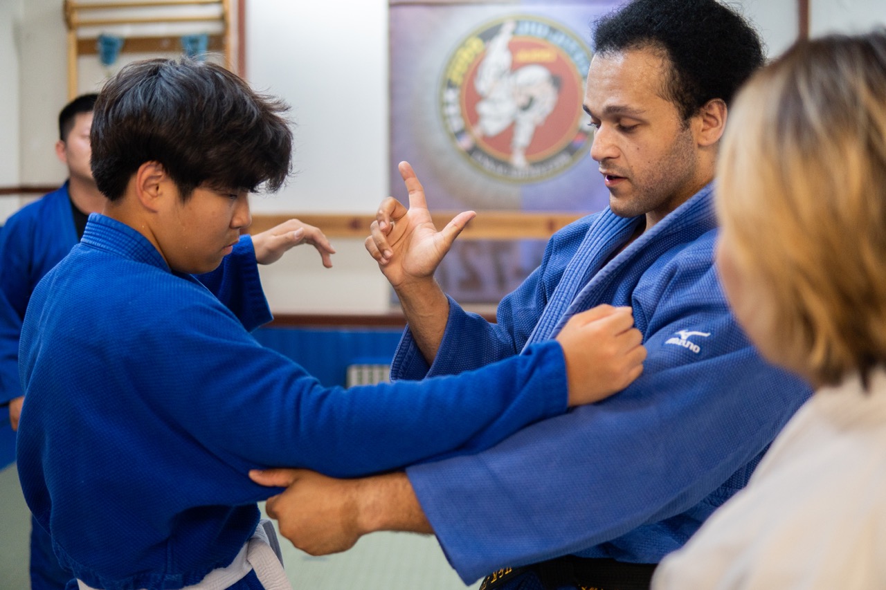 Students practicing judo techniques in a supportive environment